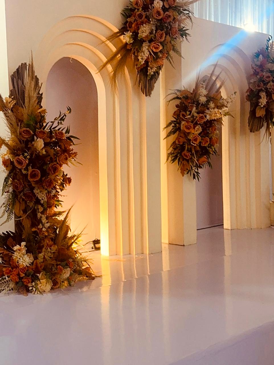 Arcos brancos em camadas com instalações florais em tons de terracota