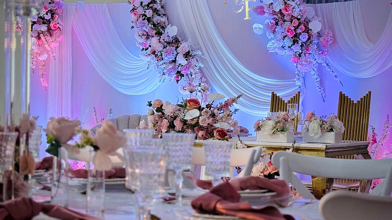 Mesa principal em rosa e dourado, com drapeados brancos e arranjos florais suspensos