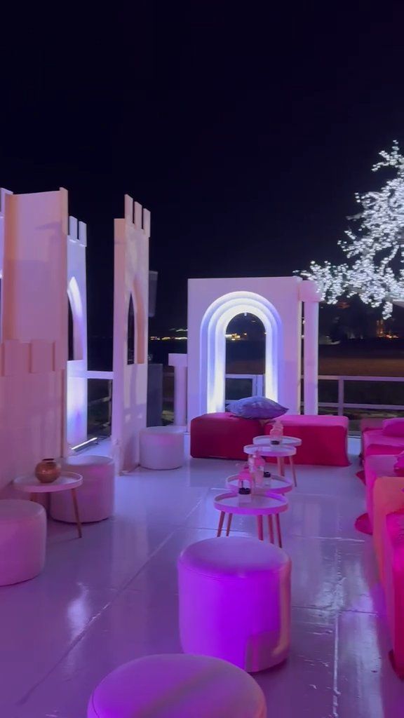 Lounge temático nocturno com muralha branca, arco iluminado e árvore de luz