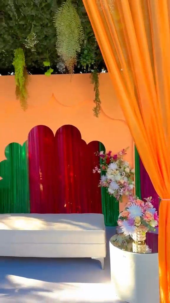 Lounge ao ar livre com painel pêssego e cortinados coloridos