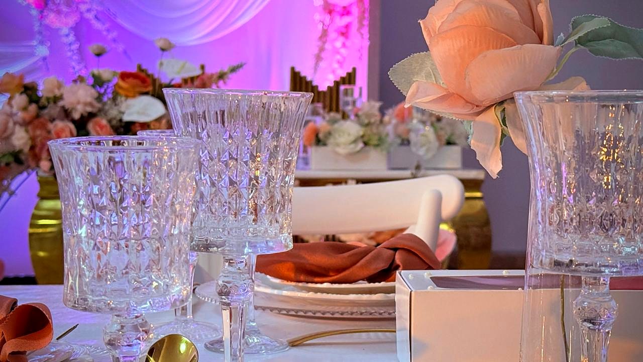 Rosa cor de pêssego em primeiro plano ao lado de taças de cristal e guardanapo terracota