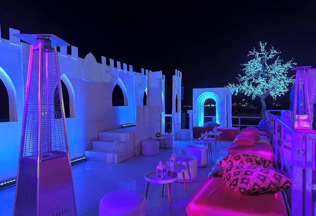 Lounge temático com castelo iluminado a azul, árvore de luzes e almofadas rosa