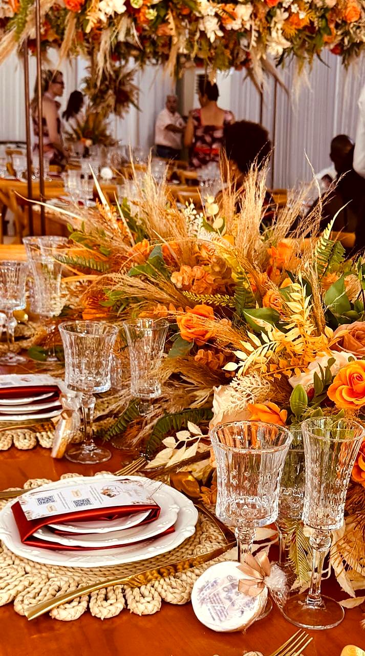 Centro de mesa em tons de laranja com gramíneas secas, rosas e taças de cristal